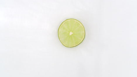 On-a-white-background-cut-into-slices-of-lime-sprinkled-with-water-spray.-Juicy-fresh-lime-in-slow-motion.